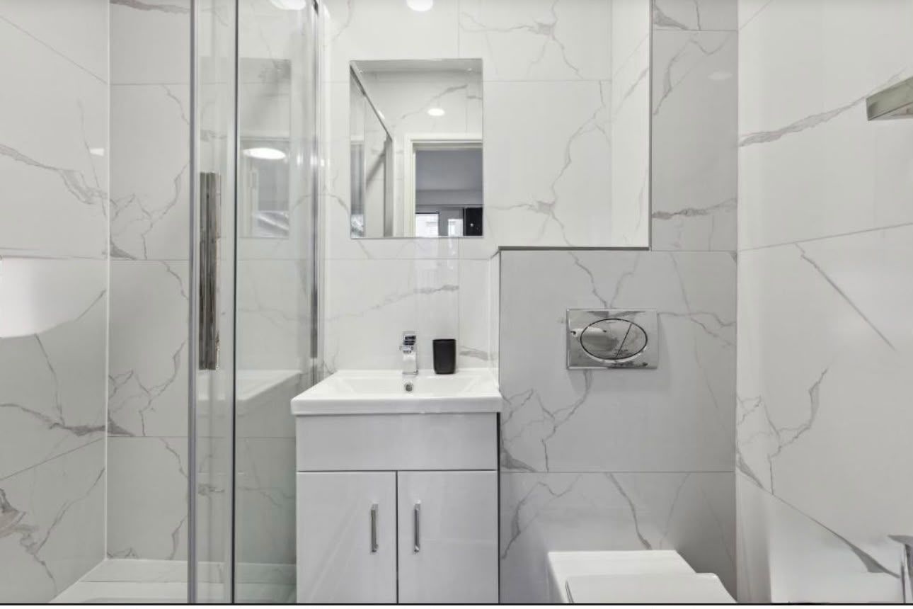 Shower room with marble-effect tiling and a glass shower enclosure