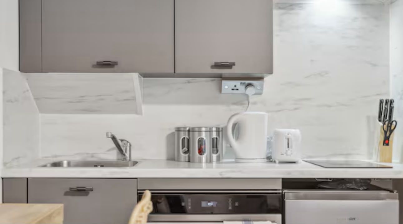 Kitchenette with oven, induction hob, sink and marble-effect splashback