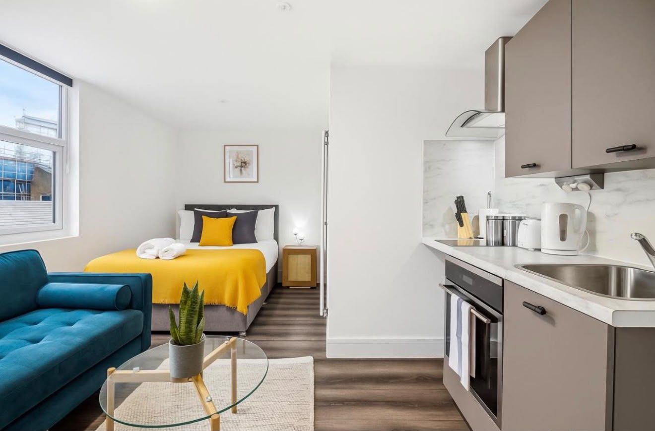 Studio with a teal sofa, bed and kitchen along one wall