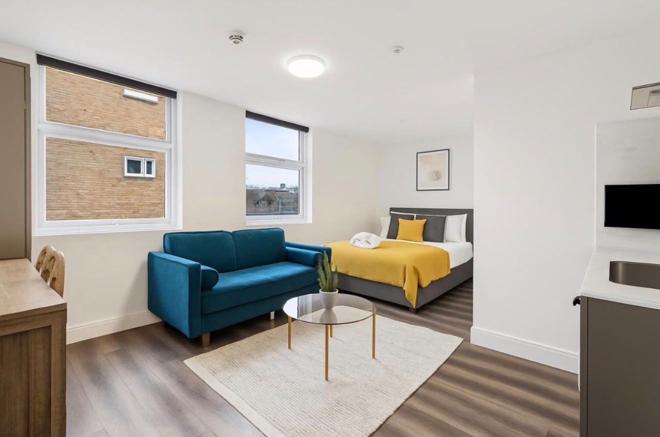 Bright studio with a teal sofa and tall windows