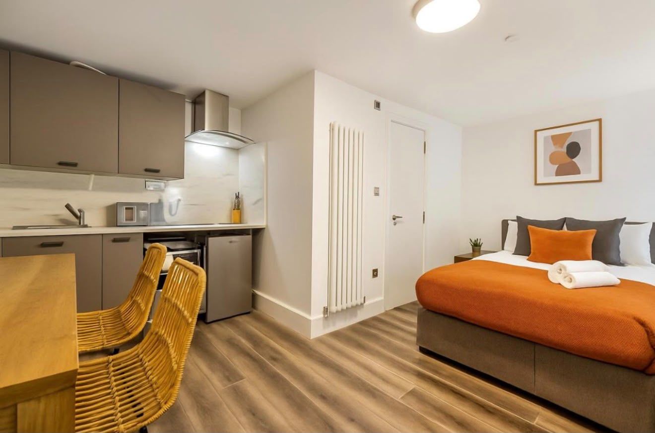 Studio with rattan dining chairs and an orange bed throw