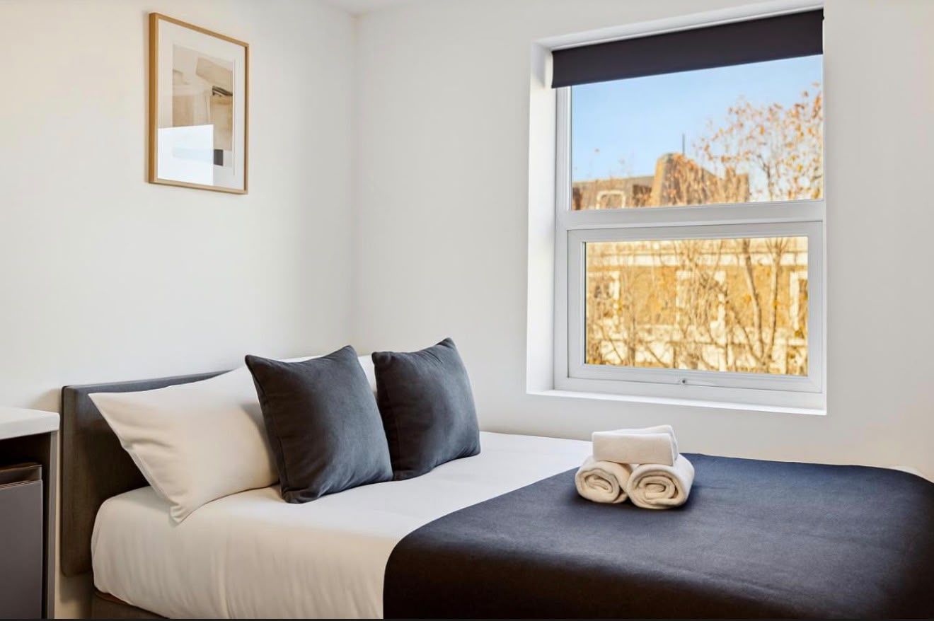 Bed with a navy throw beneath a sash window