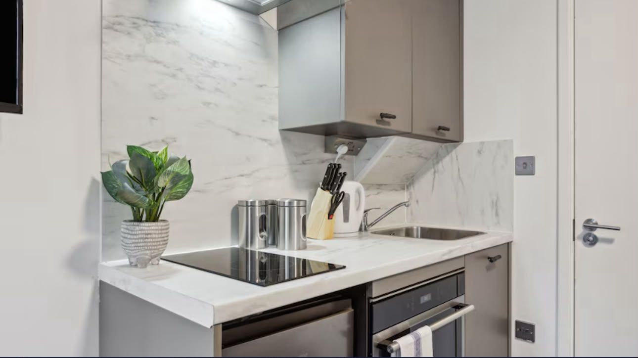 Kitchenette with induction hob, oven and marble-effect splashback